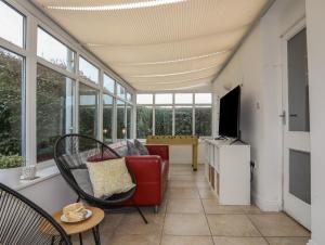 a living room with a red couch and a tv at Trearddur View in Holyhead