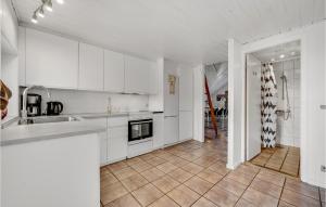 a kitchen with white cabinets and a tile floor at Pet Friendly Home In Ringkøbing in Søndervig