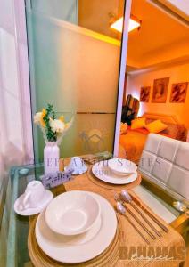 una mesa de cristal con platos blancos y un espejo en Azure Staycation by Oveecation Suites, en Manila