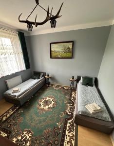 a living room with two beds and a rug at Willa u Bociana in Siemianówka