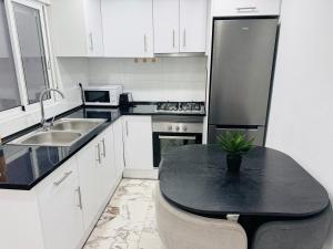 a kitchen with white cabinets and a black counter top at Apartamento Noori 1B in Vinaròs