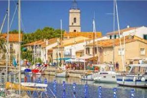 a group of boats docked in a harbor with a lighthouse at Charmante maison de ville 2 chambres avec terrasse, très calme in Marseillan