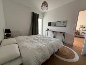 a bedroom with a white bed and a couch at Appartement 48 m2 neuf 150m de la mer A307 in Royan