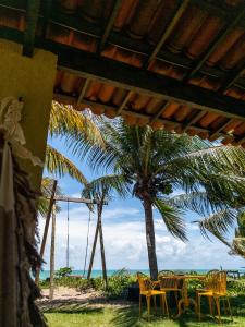 a table and chairs on the beach with a palm tree at Flat Ilha da Crôa in Barra de Santo Antônio