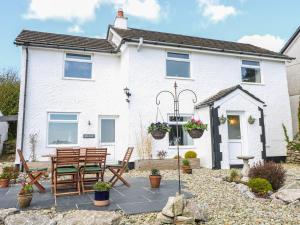 a white house with a table and chairs in front of it at Bryn Uchaf in Benllech