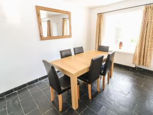 a dining room with a wooden table and black chairs at Bryn Uchaf in Benllech +6 photos