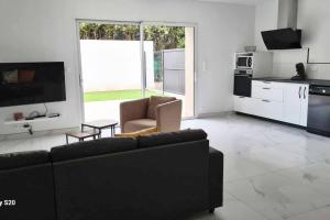 a living room with a black couch and a kitchen at Appartement Le Marcky in Graulhet