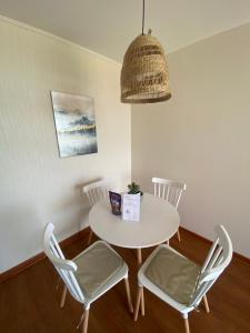 a white table with chairs and a pendant light at Departamento San Fernando in San Fernando +10 photos
