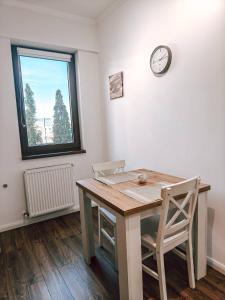 a table with two chairs and a clock on a wall at Luminia Apartment in Cluj-Napoca
