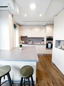 a kitchen with white cabinets and a counter with two stools at Lakeside Apartment By Iulius Mall in Cluj-Napoca