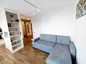 a living room with a blue couch and a shelf at Lakeside Apartment By Iulius Mall in Cluj-Napoca