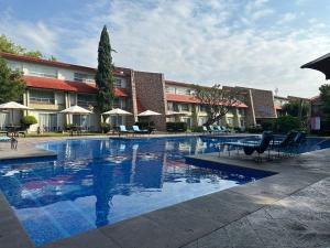 a swimming pool with chairs and umbrellas in a hotel at Hotel Real de Minas Tradicional in Querétaro