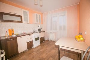 a kitchen with white cabinets and a table with a bowl of fruit at Apartment On Kievskaya 90 in Tomsk