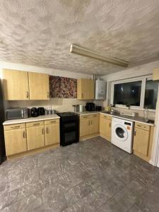 a kitchen with wooden cabinets and a washer and dryer at Sheffield Serenity in Heeley