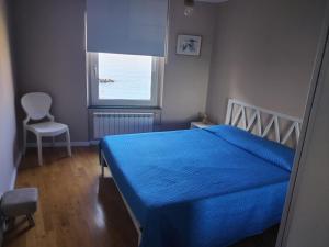 a bedroom with a blue bed and a window at Casa Tabata fronte mare in Genoa