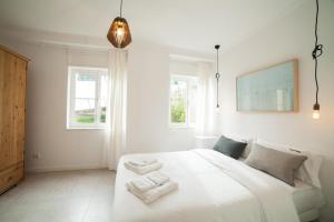 a white bedroom with a large white bed with two towels at FLH Estrela Comfortable Flat in Lisbon