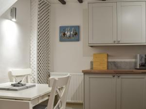 a kitchen with white cabinets and a table and chairs at Maisies Cottage in Wirksworth