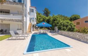 basen z parasolem i krzesłami oraz budynek w obiekcie 2 Bedroom Stunning Apartment In Krk w Krku +25 zdjęć