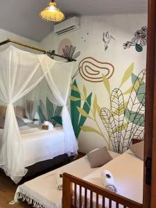 a bedroom with two beds and a wall with flowers at Pousada Quintal dos Sonhos Xandó Caraiva in Caraíva