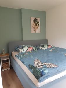 a bed with a blue comforter and pillows on it at Schöne 120-qm-Ferienwohnung - Sonnenterrasse - Stadtgrenze Lübeck in Stockelsdorf