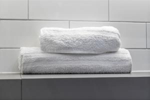 three towels are stacked on a shelf in a bathroom at Apartment in Birmingham City Centre - Free Parking Underground in Birmingham +57 photos
