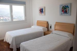 deux lits dans une chambre blanche avec une fenêtre dans l'établissement Precioso piso con vistas a las Islas Cíes, à Baiona 17 autres photos