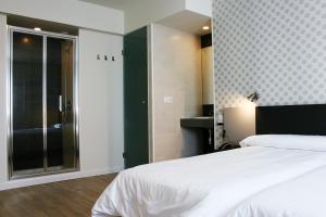 a bedroom with a white bed and a bathroom at Checkin Urban Nevada in Granada