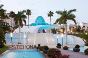 a resort with a pool and palm trees and a building at Loving Mediterranean Home in Estepona