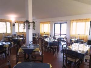 a dining room with tables and chairs and windows at Nuraghe Ruiu Piazzole campeggio Blue Holiday in Norbello