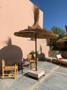 a patio with a large straw umbrella and chairs at Dar Almajula in Essaouira +27 photos