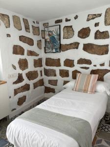 a bedroom with a stone wall with a bed at Hacienda de las Indias, Trinidad in Granadilla de Abona