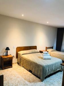 a bedroom with two beds and a dresser with a night stand at La Familia Hotel in Puerto Iguazú