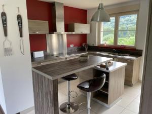 a kitchen with a counter with two stools in it at Gîte le Beauchamp in Les Hautes-Rivières