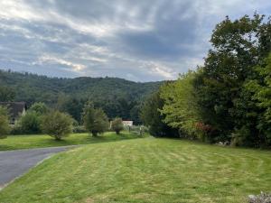 a road with a field of grass and trees at Gîte le Beauchamp in Les Hautes-Rivières