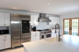 a kitchen with a stainless steel refrigerator and a sink at Modern Comfy Retreat Patio Outdoor Salt Hot Tub in East Hampton
