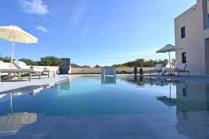 a swimming pool with chairs and an umbrella at Villa De An in Zakynthos