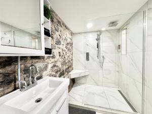 a white bathroom with a sink and a shower at Le Montcalm Chutes-Montmorency in Boischâtel
