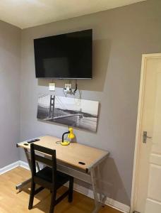 a desk with a chair and a television on a wall at Linie Guest house in Alberton +14 photos