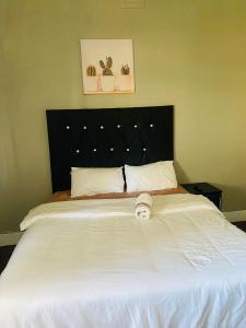 a bedroom with a large white bed with a black headboard at Linie Guest house in Alberton