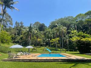 a swimming pool in a park with palm trees at Sítio Mato Dentro in Atibaia