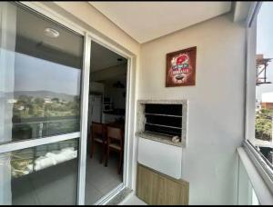 ein Zimmer mit Fenster und Blick auf ein Wohnzimmer in der Unterkunft Canto dos pássaros in Governador Celso Ramos