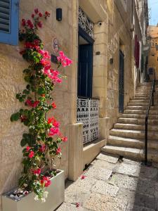 un bâtiment avec des fleurs roses sur le côté dans l'établissement Moon Malta Boutique Stay with Rooftop Pool & Sea Views of Valletta, Grand Harbour & Three Cities, à Cospicua