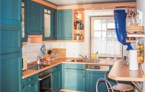 a kitchen with blue cabinets and a sink and a table at 2 Bedroom Amazing Apartment In Koserow in Ostseebad Koserow