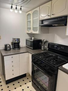 een keuken met witte kasten en een kookplaat oven bij Bright Garden Suite Across From Park in Kitsilano in Vancouver +8 foto's