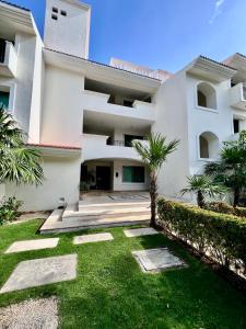 une maison blanche avec une pelouse devant dans l'établissement studio au coeur de la marina, à Puerto Aventuras