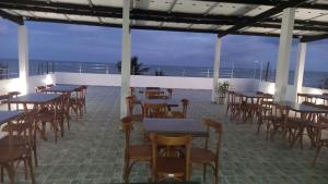 a restaurant with tables and chairs and the ocean at Tamandaré Divers Resort in Tamandaré