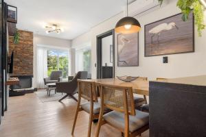 a dining room and living room with a table and chairs at Res. Tribeca 350m Rua Coberta by Achei Gramado in Gramado