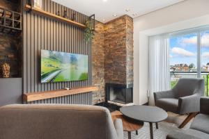 a living room with a tv and a fireplace at Res. Tribeca 350m Rua Coberta by Achei Gramado in Gramado