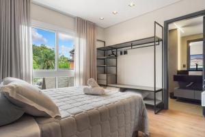 a bedroom with a large bed and a large window at Res. Tribeca 350m Rua Coberta by Achei Gramado in Gramado