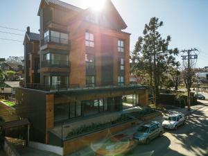 a building with two cars parked in front of it at Res. Tribeca 350m Rua Coberta by Achei Gramado in Gramado